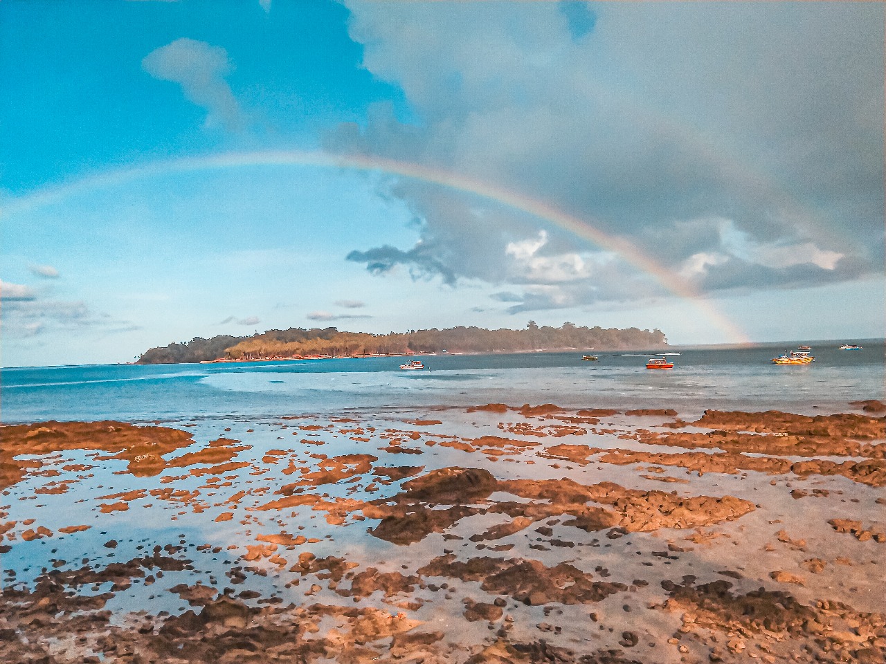 Rainbow over a rocky Andaman beach shoreline